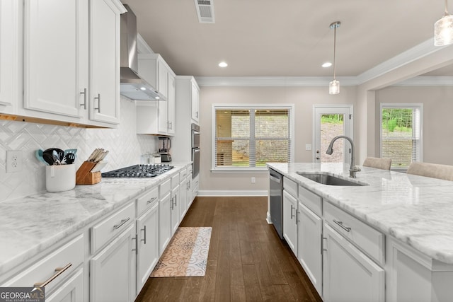 kitchen with white cabinets, wall chimney exhaust hood, stainless steel appliances, and hanging light fixtures