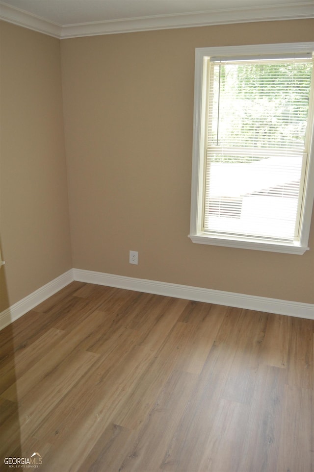 empty room with ornamental molding and light wood-type flooring