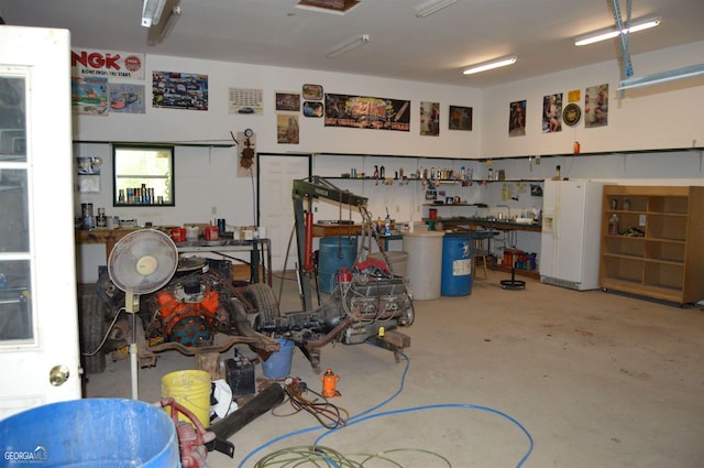 garage featuring white refrigerator with ice dispenser and a workshop area