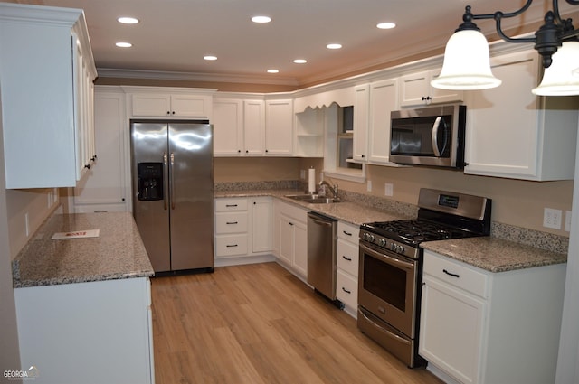 kitchen with hanging light fixtures, stainless steel appliances, sink, and white cabinets