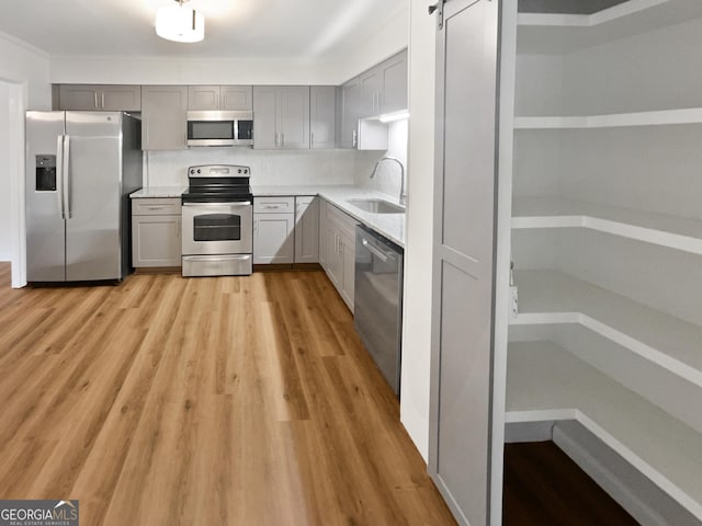 kitchen featuring appliances with stainless steel finishes, a barn door, gray cabinetry, and sink