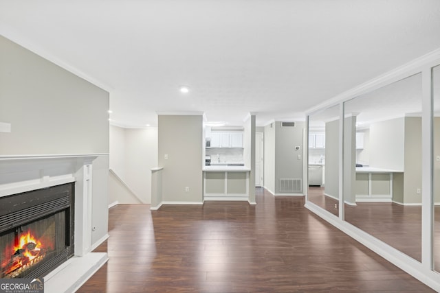 unfurnished living room featuring crown molding and dark hardwood / wood-style flooring