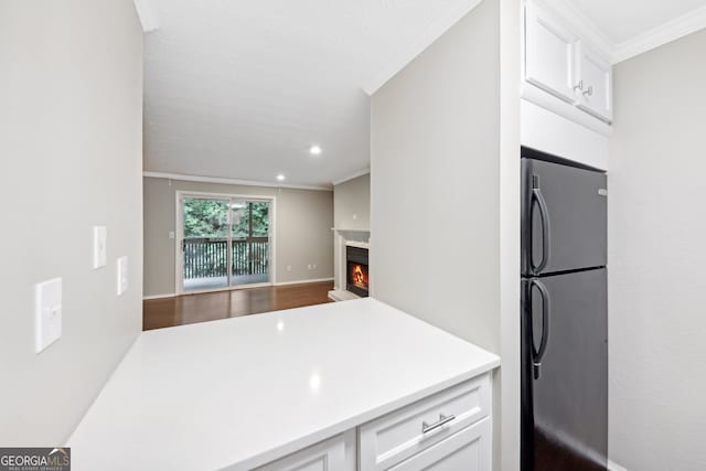 kitchen featuring hardwood / wood-style flooring, white cabinetry, ornamental molding, and fridge