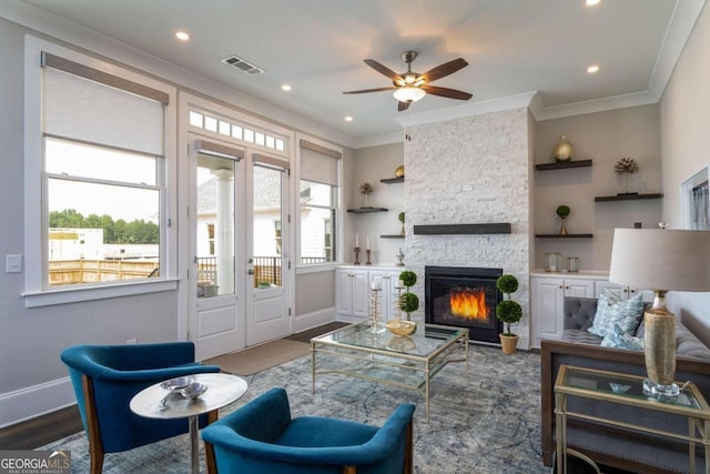 living room with crown molding, dark hardwood / wood-style floors, ceiling fan, and a fireplace