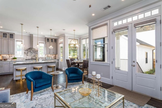 living room with ornamental molding, dark hardwood / wood-style floors, an inviting chandelier, and french doors