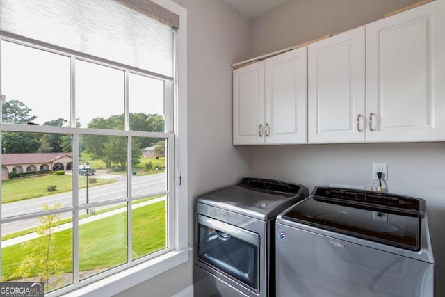 clothes washing area featuring cabinets and washer and dryer