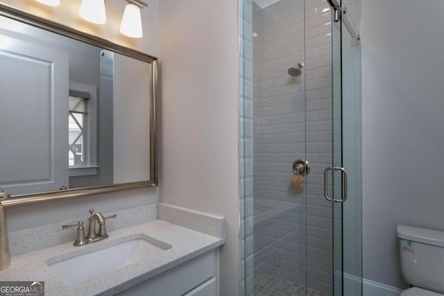 bathroom with vanity, toilet, and a shower with door