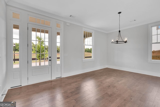 foyer featuring crown molding, dark hardwood / wood-style flooring, a chandelier, and a wealth of natural light