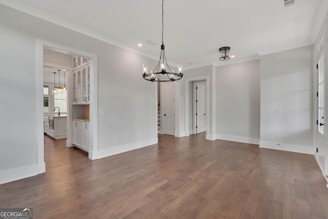 unfurnished dining area with dark hardwood / wood-style flooring, sink, crown molding, and a chandelier