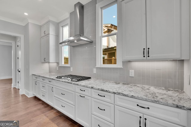 kitchen featuring white cabinetry, stainless steel gas cooktop, wall chimney range hood, and light hardwood / wood-style flooring