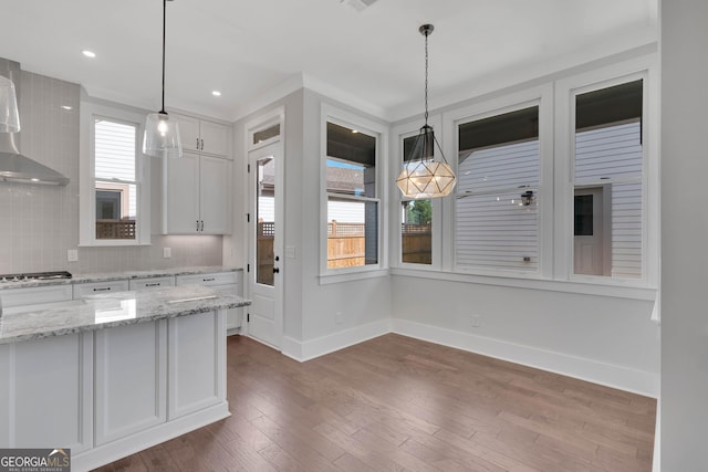 kitchen with white cabinetry, light stone counters, decorative backsplash, and hanging light fixtures