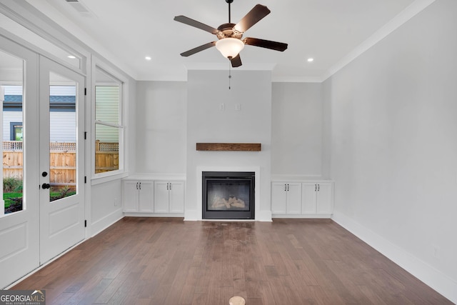 unfurnished living room featuring crown molding, ceiling fan, dark wood-type flooring, and french doors