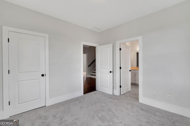 unfurnished bedroom featuring connected bathroom and light colored carpet