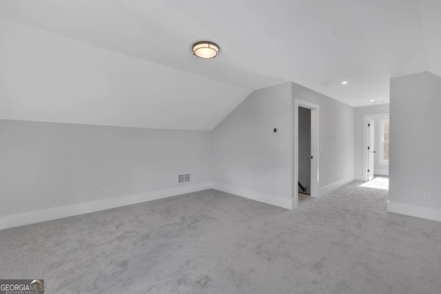 additional living space with vaulted ceiling and light carpet