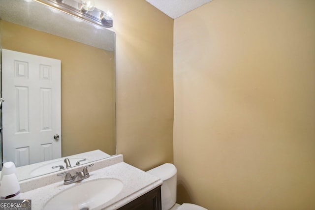 bathroom featuring vanity, toilet, and a textured ceiling