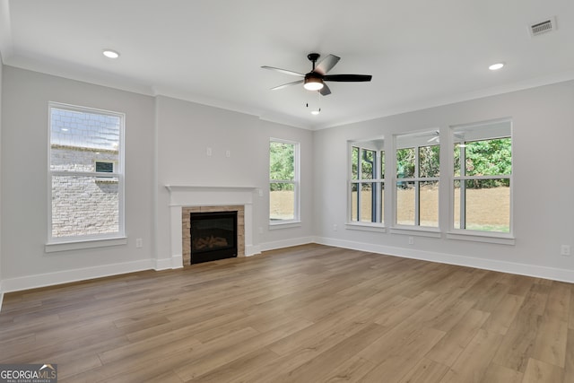 unfurnished living room featuring light hardwood / wood-style flooring, a tiled fireplace, ceiling fan, and ornamental molding