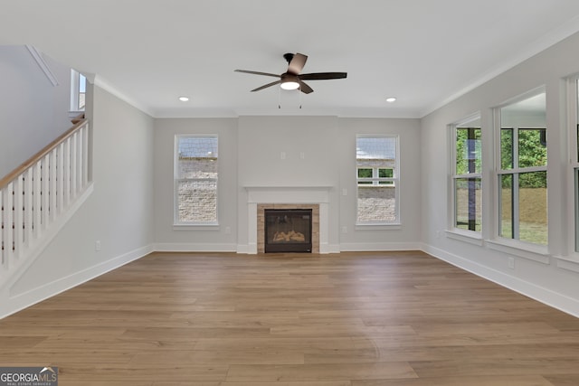 unfurnished living room featuring ceiling fan, light hardwood / wood-style flooring, a fireplace, and a healthy amount of sunlight