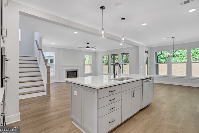 kitchen featuring light wood-type flooring, a center island with sink, stainless steel dishwasher, and sink