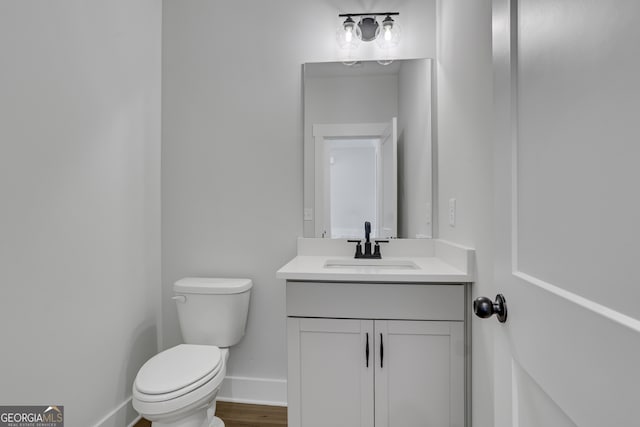 bathroom featuring wood-type flooring, vanity, and toilet