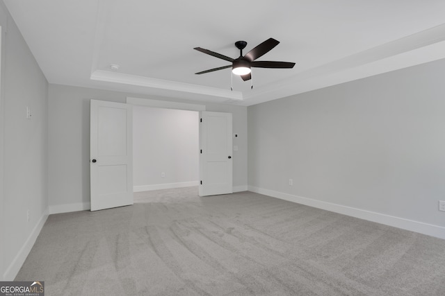 carpeted spare room with ceiling fan and a raised ceiling