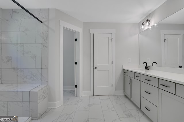 bathroom with a tile shower and vanity