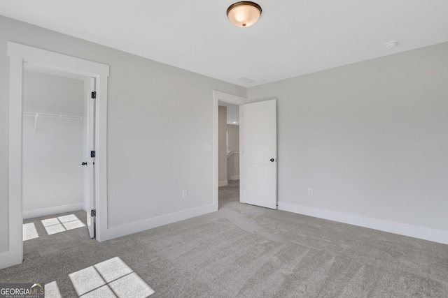 unfurnished bedroom with carpet flooring, a spacious closet, and a closet