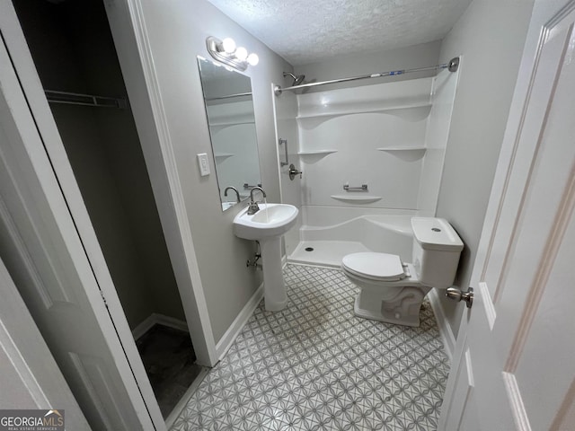 bathroom with a shower, a textured ceiling, and toilet