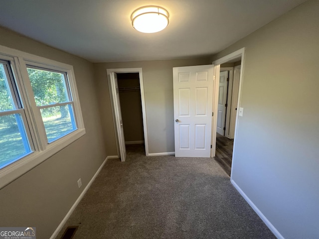 unfurnished bedroom featuring dark colored carpet and a closet