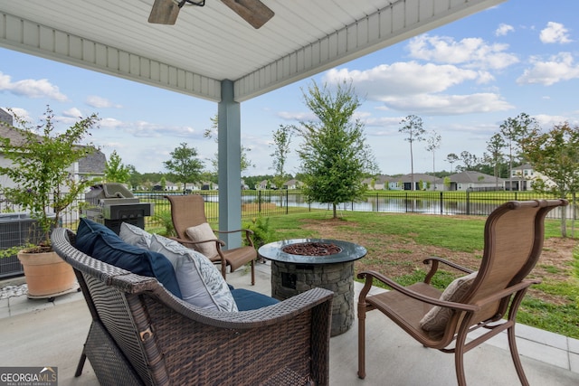 view of patio / terrace featuring a water view, ceiling fan, and an outdoor fire pit