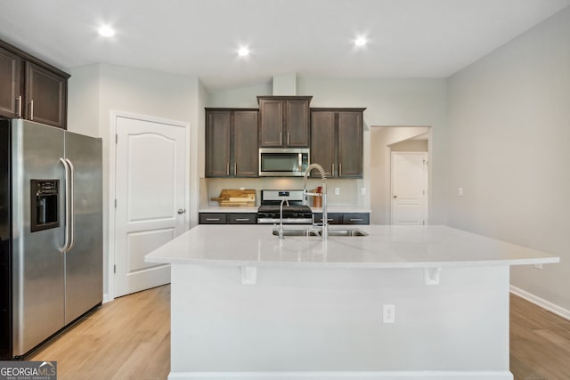 kitchen with appliances with stainless steel finishes, sink, an island with sink, and dark brown cabinets