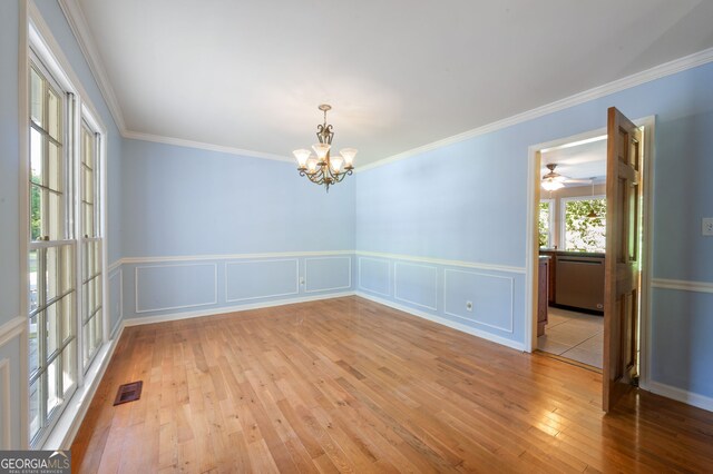 empty room featuring hardwood / wood-style floors, ceiling fan with notable chandelier, and ornamental molding