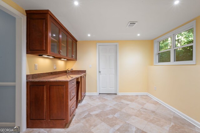 kitchen featuring light tile patterned flooring, sink, and dark stone countertops