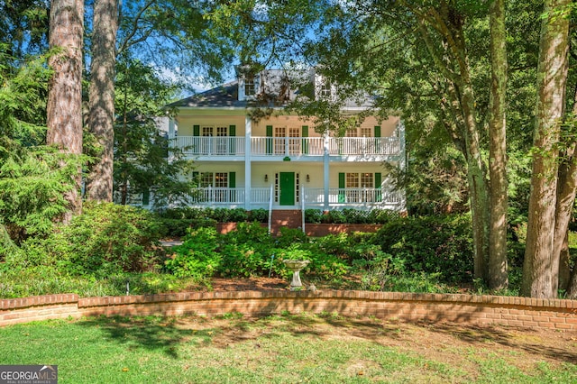 rear view of house featuring a balcony and a yard