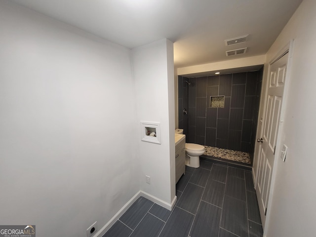 bathroom featuring vanity, toilet, and tiled shower