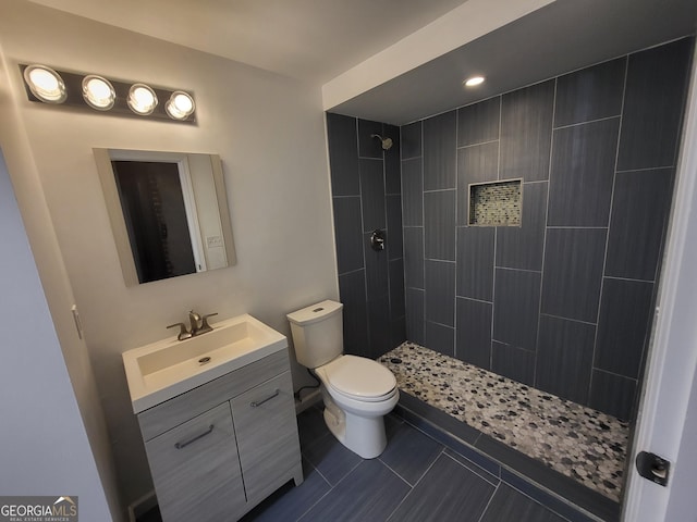 bathroom featuring a tile shower, vanity, toilet, and tile patterned floors