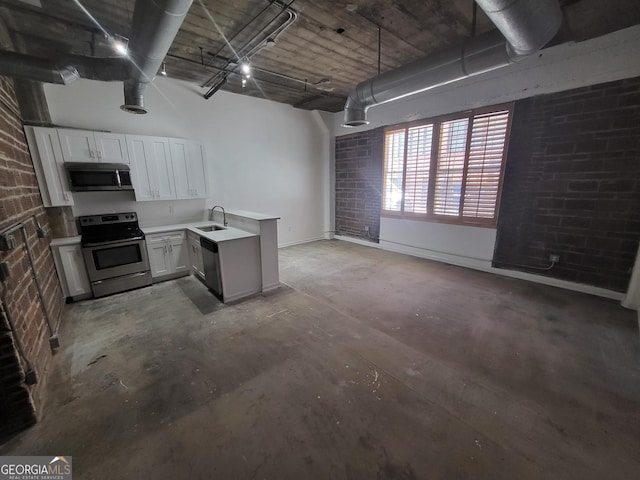 kitchen with white cabinetry, sink, brick wall, and appliances with stainless steel finishes