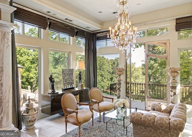 sunroom featuring plenty of natural light, ornate columns, and a chandelier