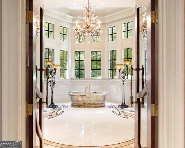 interior space with plenty of natural light, ornamental molding, and a notable chandelier