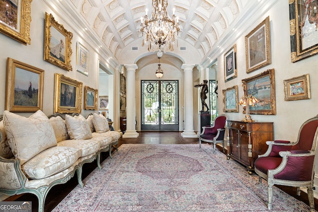 living room with a towering ceiling, wood-type flooring, ornate columns, and an inviting chandelier