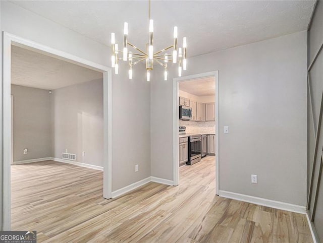 unfurnished dining area featuring light hardwood / wood-style flooring and an inviting chandelier