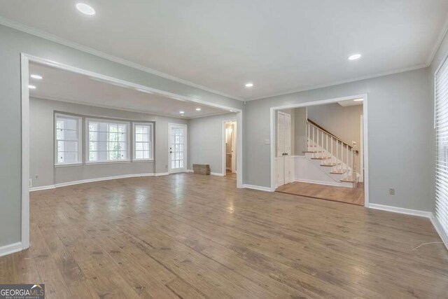 unfurnished living room featuring hardwood / wood-style floors and ornamental molding