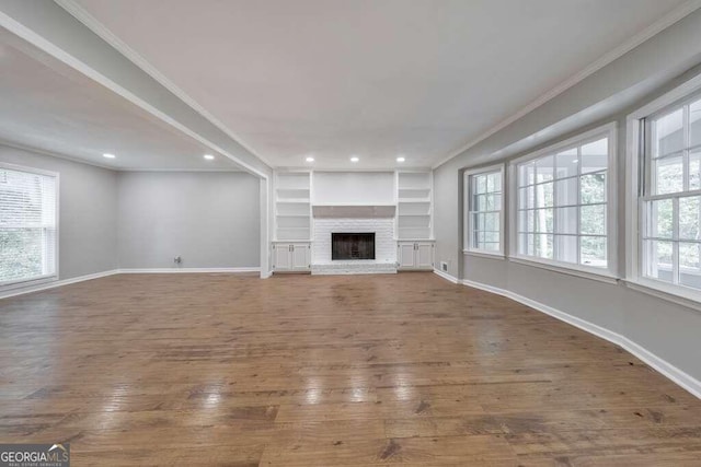 unfurnished living room with a fireplace, a healthy amount of sunlight, and hardwood / wood-style flooring