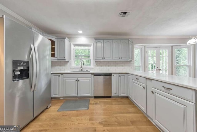 kitchen featuring appliances with stainless steel finishes, light hardwood / wood-style floors, decorative backsplash, and sink