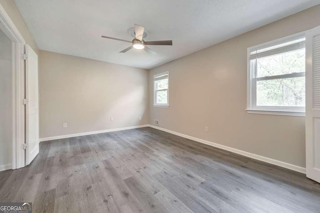 spare room featuring ceiling fan, hardwood / wood-style floors, and a healthy amount of sunlight