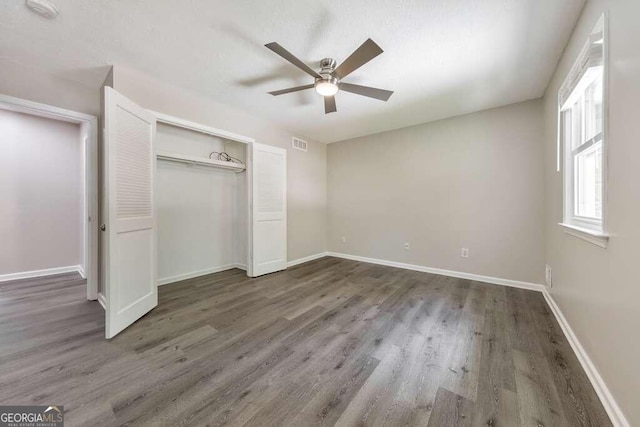 unfurnished bedroom featuring ceiling fan, wood-type flooring, and a closet