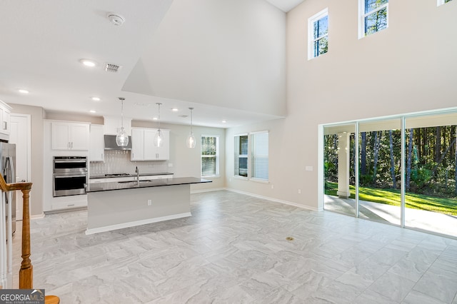 kitchen featuring white cabinets, decorative backsplash, pendant lighting, and a kitchen island with sink