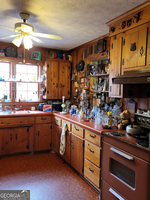 kitchen featuring a textured ceiling, ceiling fan, range, and sink