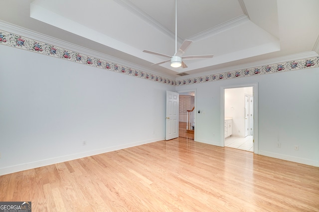 tiled empty room with ceiling fan, crown molding, and a tray ceiling