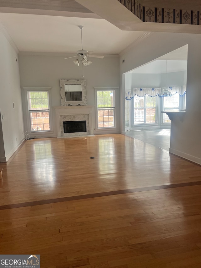 unfurnished living room with ceiling fan, a high end fireplace, hardwood / wood-style floors, and crown molding