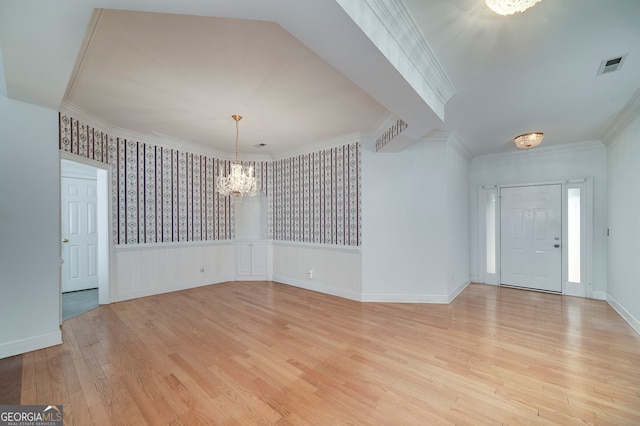 foyer entrance featuring ornamental molding, an inviting chandelier, and light wood-type flooring